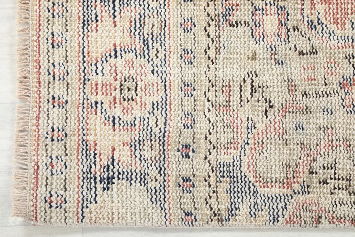 Detail of the rug's border and fringe, showing the intricate patterns and the natural ivory fringe.