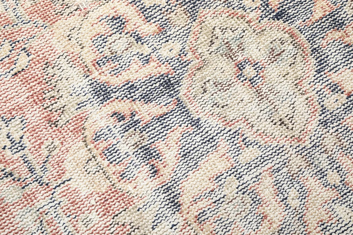 Extreme close-up of the hand-knotted wool pile, revealing the texture, knotting, and areas of low pile.