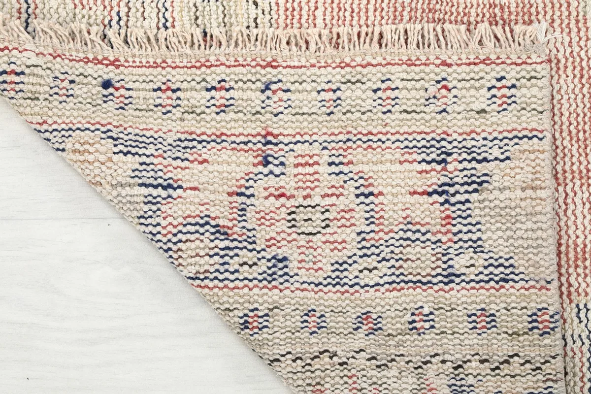 View of the back of the rug folded, showing the cotton foundation and the reverse of the hand-knotted construction.