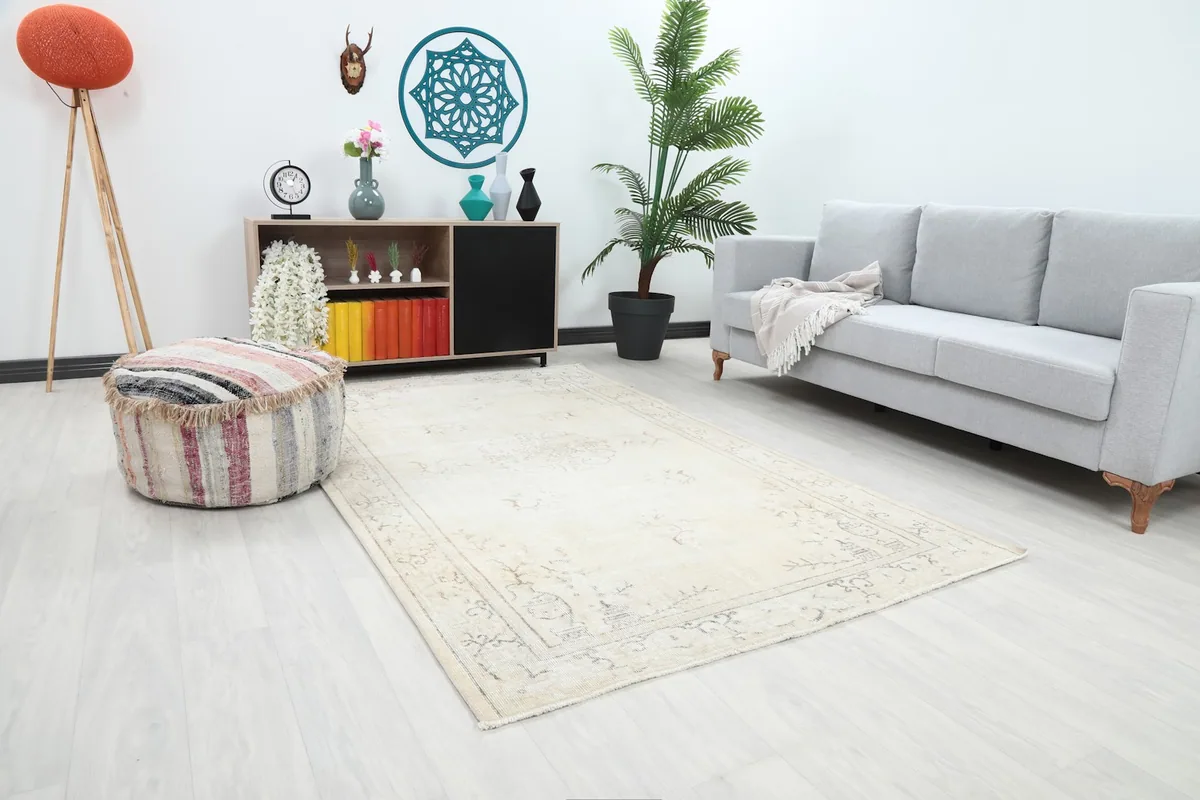 Angled view of the beige Anatolian rug in a room, showing its placement in front of a sofa