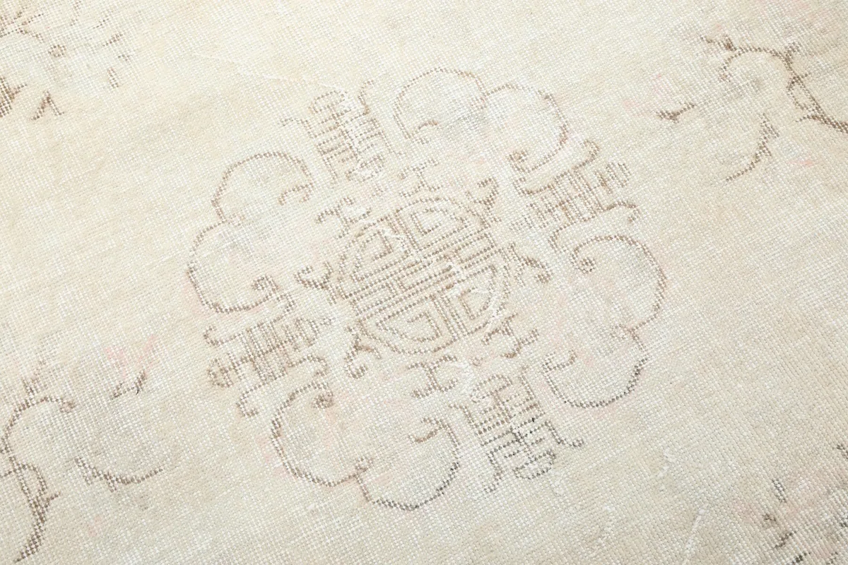 Close-up of the intricate central medallion pattern on the vintage beige wool rug