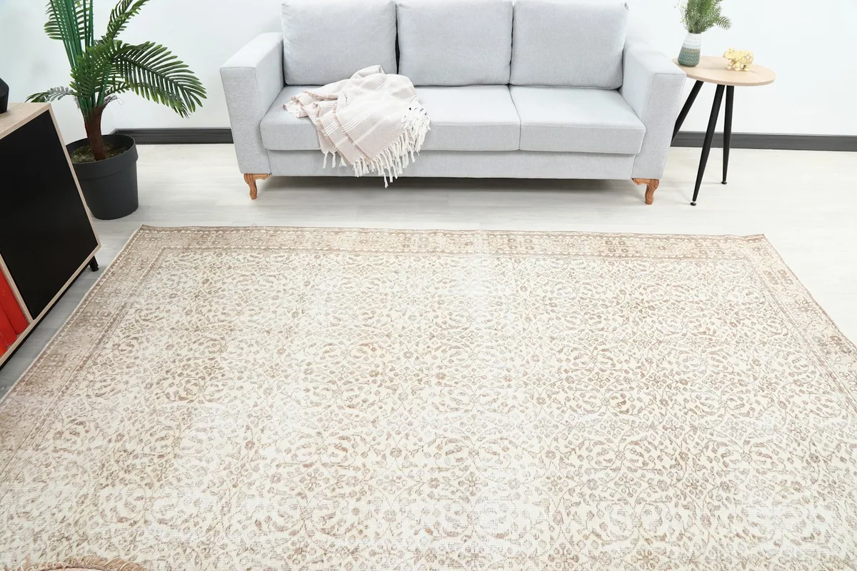 View of the ivory and tan rug in a living room, centered in front of a gray sofa.