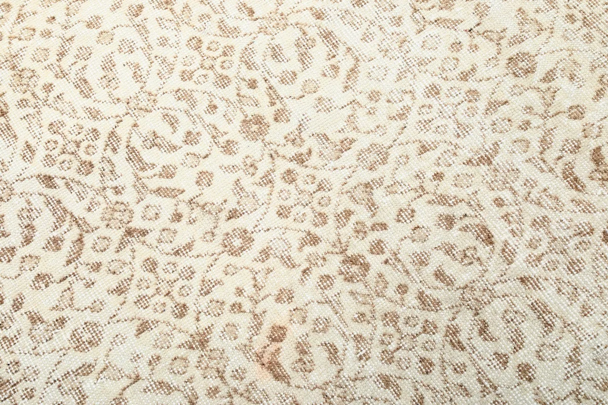 Close-up of the intricate tan floral motifs on the ivory background, showing texture and patina.
