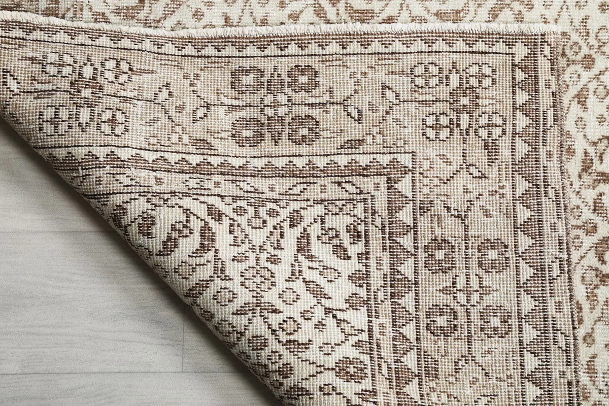 Detailed view of the rug's corner, showing the hand-knotted construction and fringe.