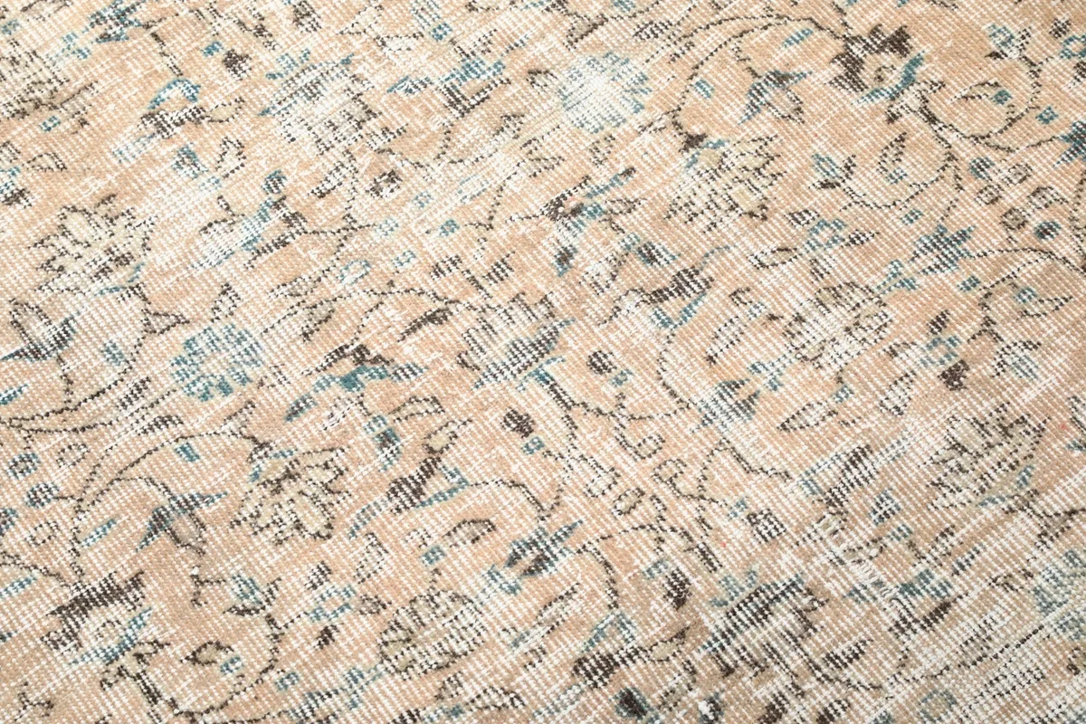 Detailed close-up of the rug's wool pile, showing the intricate floral design in beige, blue, and gray.