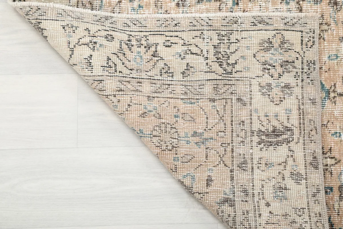 Underside of the rug with a corner folded, revealing the hand-knotted cotton foundation.