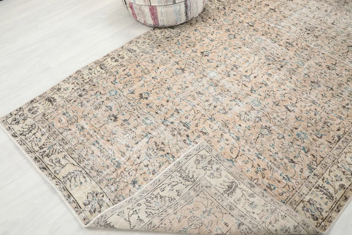 Corner of the rug folded back, showing the cotton foundation and the reverse side of the knotting.