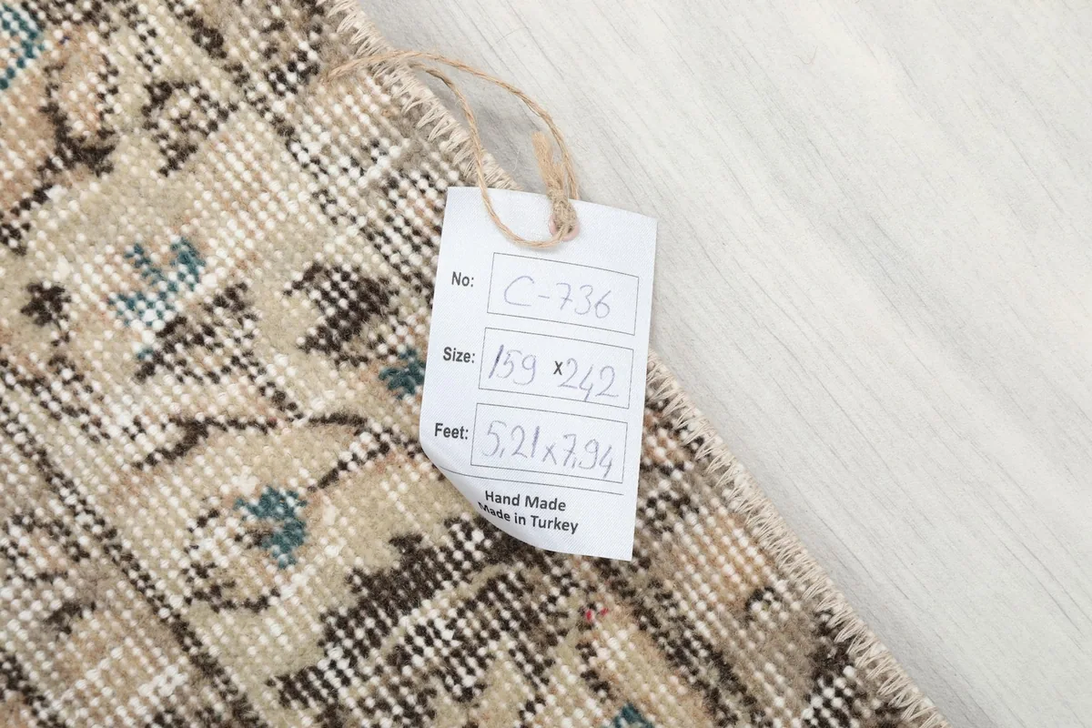 Close-up of the rug's tag, displaying its unique identifier C-736 and dimensions in cm and feet.