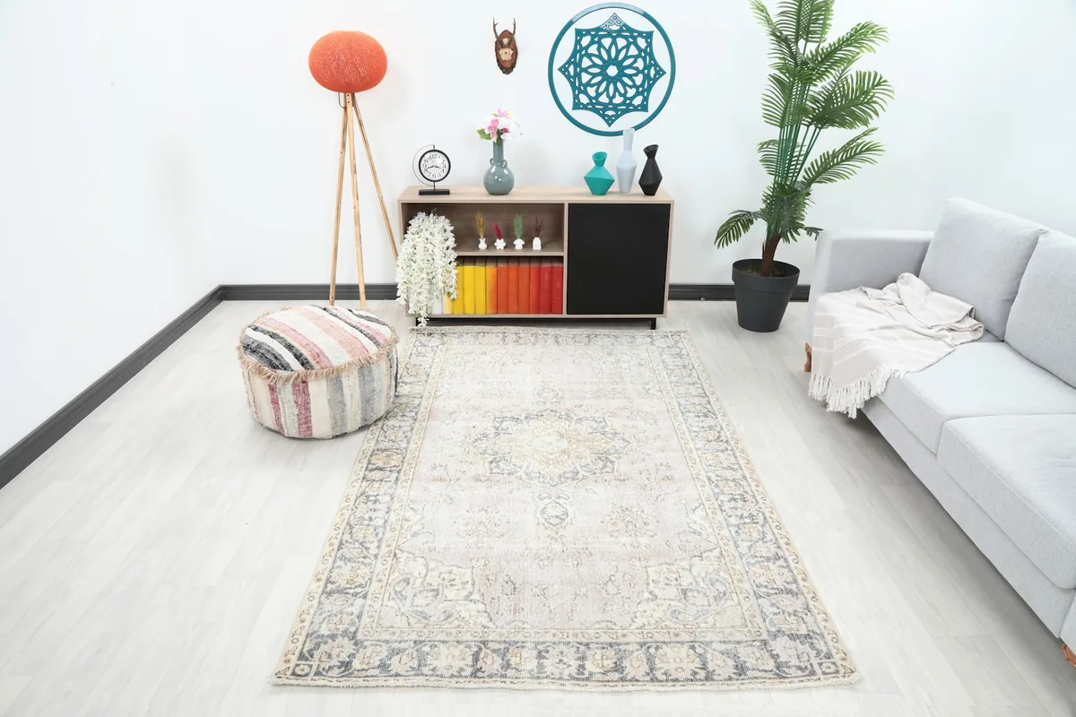 Vintage rose and gray rug displayed in a living room setting with a sofa and cabinet
