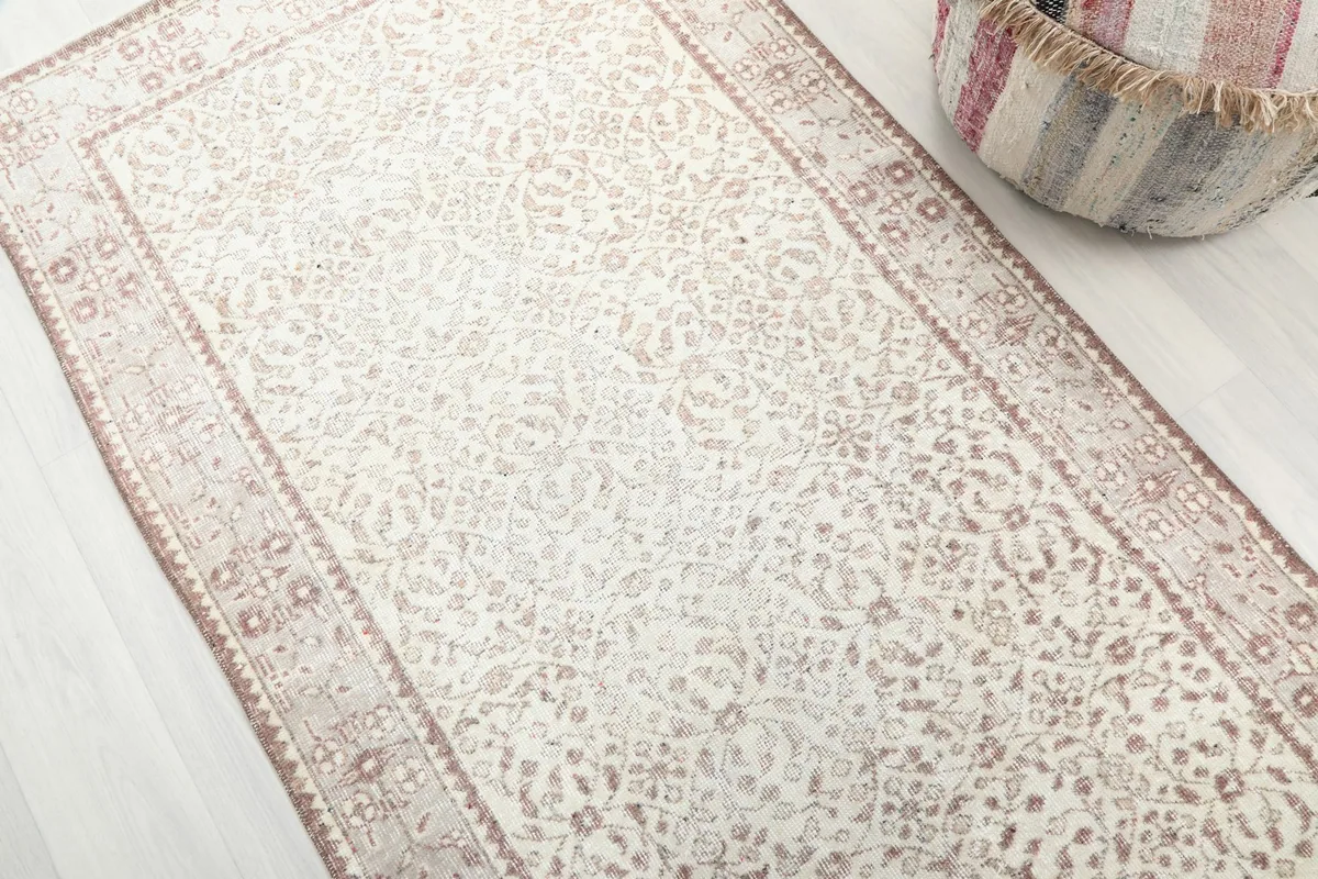 Angled view highlighting the soft rose floral patterns on the ivory field of the rug