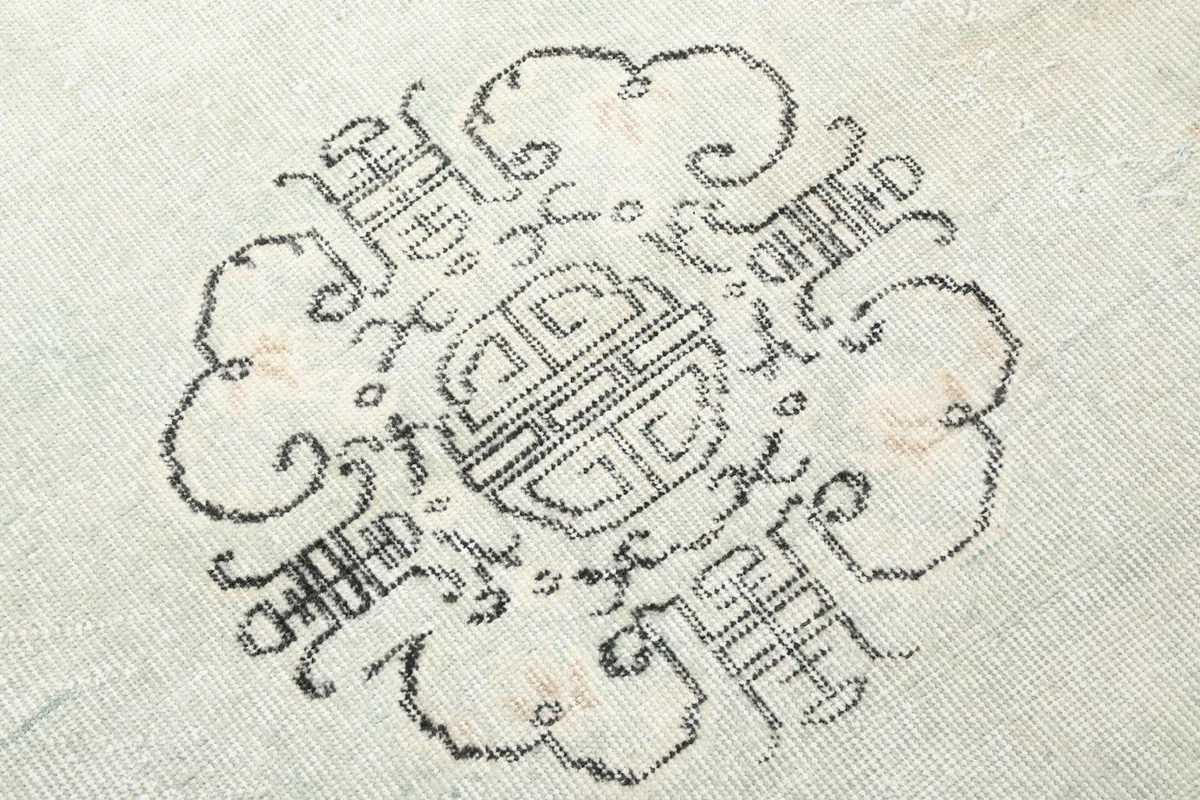 Extreme close-up of the intricate charcoal medallion pattern, showing knot detail and color variations.