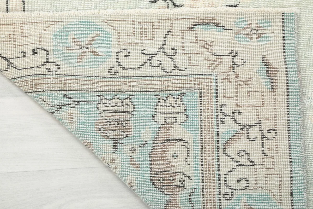 Detailed view of the rug's corner folded to show the back of the hand-knotted cotton foundation.