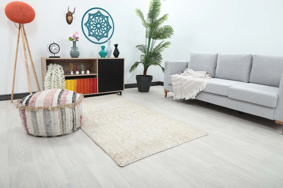 Angle view of the ivory floral rug in a room, showing its placement relative to a sofa and ottoman