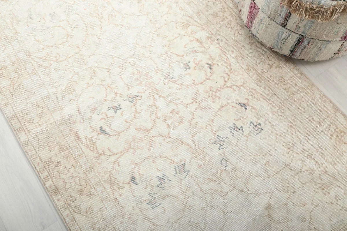 Detailed view of the rug's surface, revealing the intricate floral motifs in ivory and tan hues