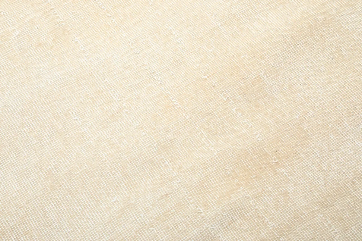 Detailed view of the low wool pile and hand-knotted texture of the ivory rug.