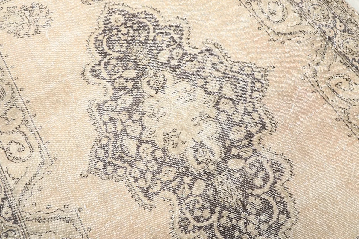 Close-up of the central gray medallion pattern on the beige vintage rug