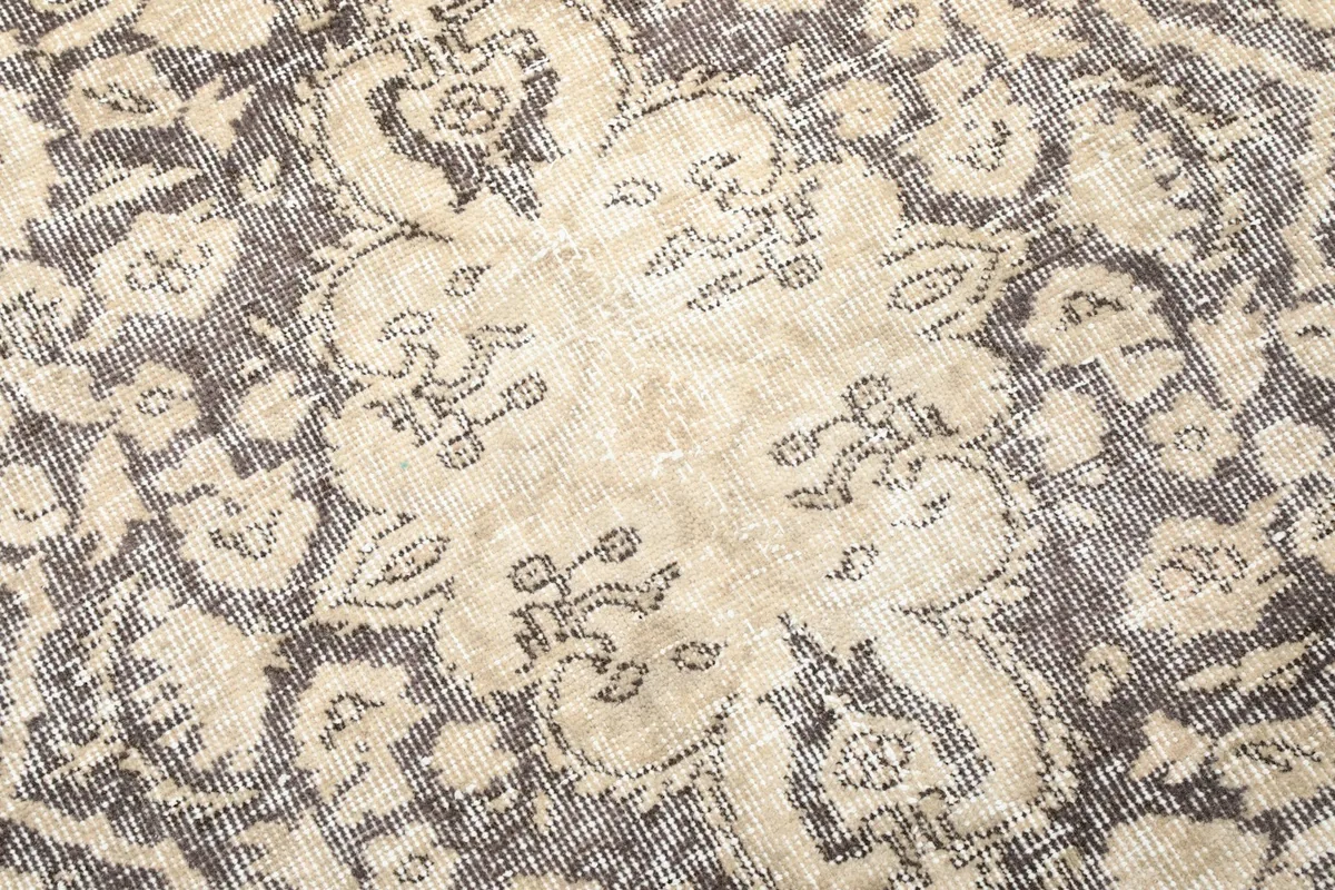 Detailed view of the intricate gray patterns and beige faded areas on the rug's pile