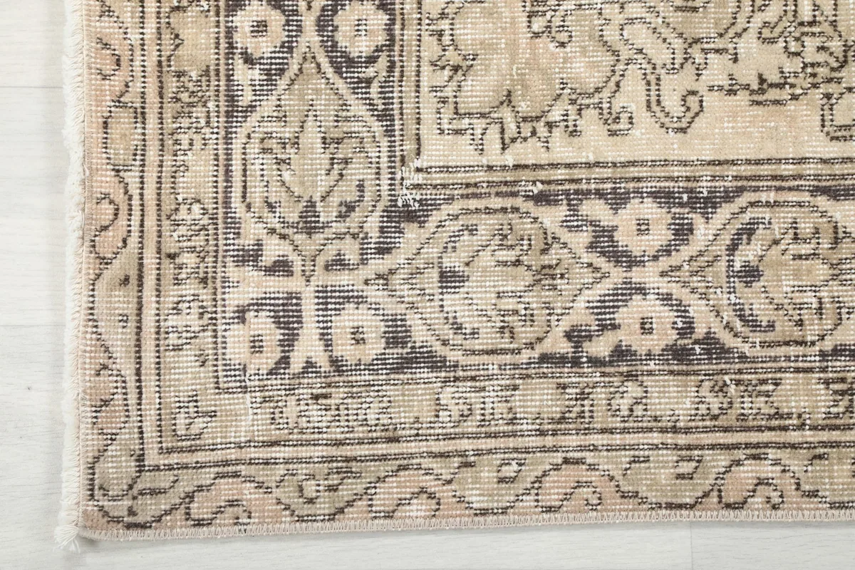 Corner detail of the vintage rug, showing the patterned border and fringe