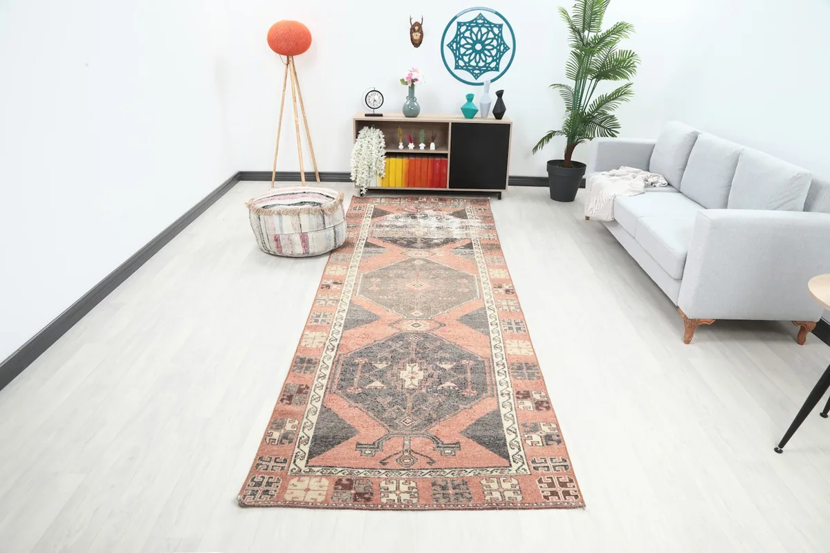 Long shot of the rust and gray runner rug in a modern living space with light flooring and a gray sofa.