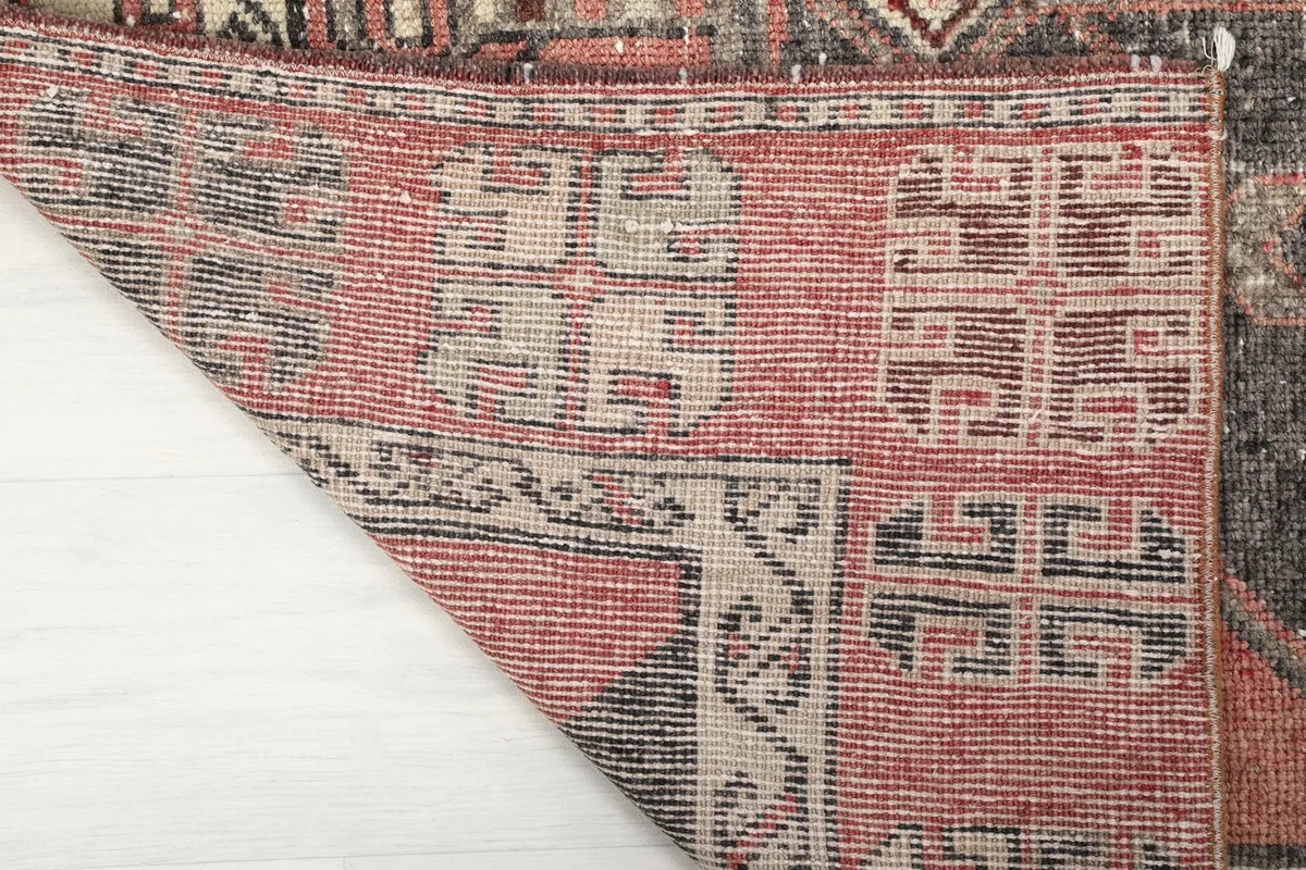 Close-up of the back of the rug and a folded edge, showing the tight knotting and cotton foundation.