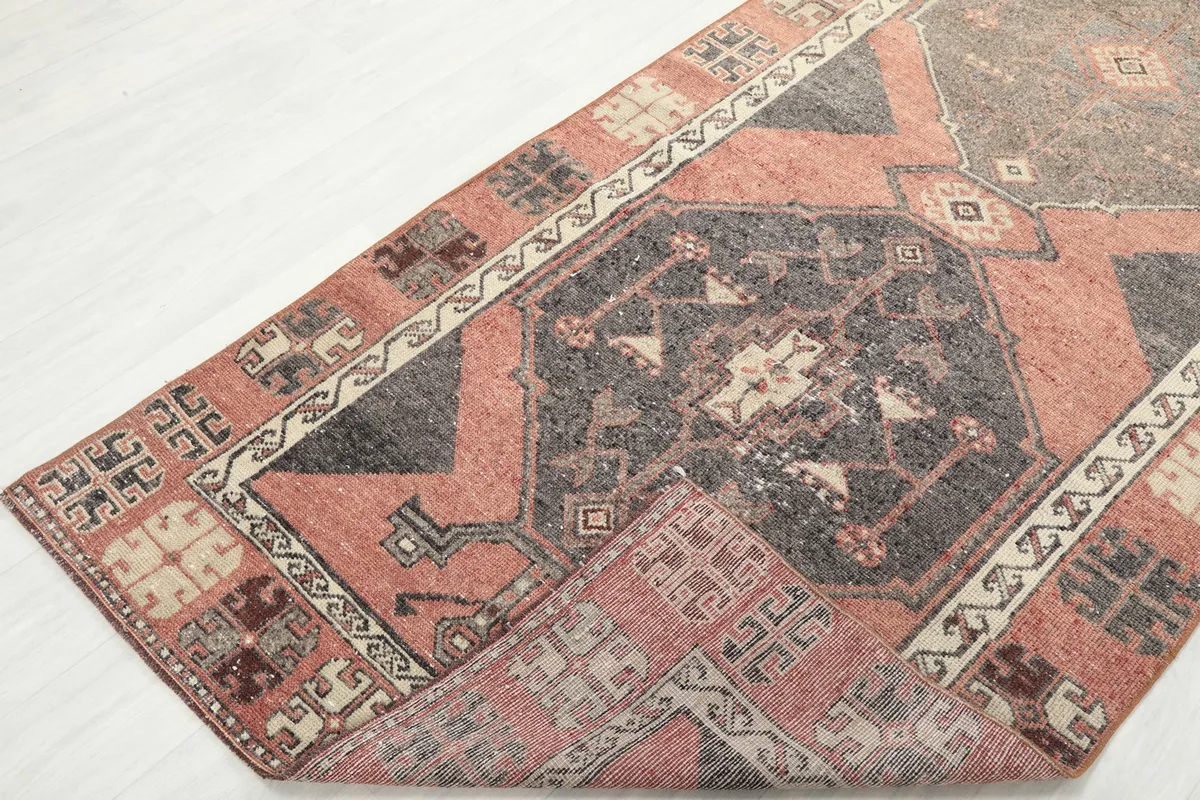 Corner of the runner rug folded back, revealing the reverse side and the construction of the hand-knotted wool.