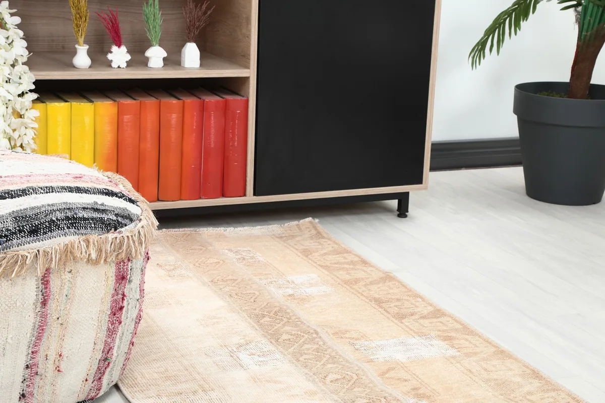 Close-up of the runner rug next to a colorful ottoman and shelving unit in a room