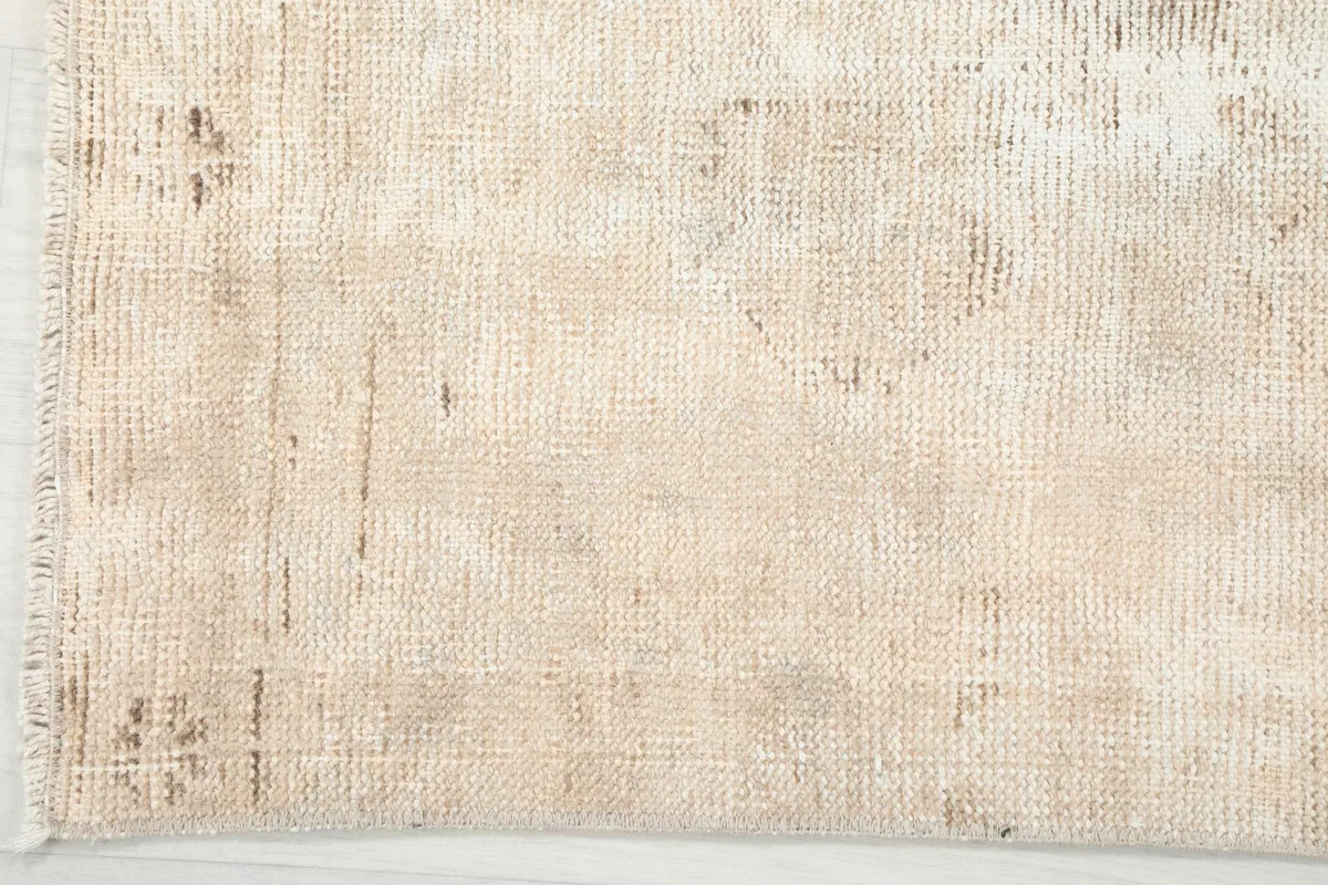 Detail of the rug's edge, revealing the worn patina and underlying cotton foundation