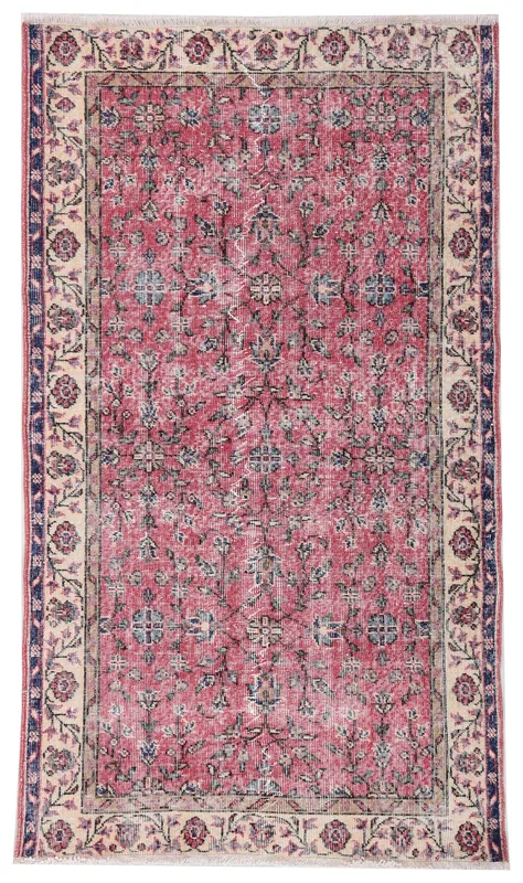 Full overhead view of a rose and cream floral vintage Anatolian rug on a white background.