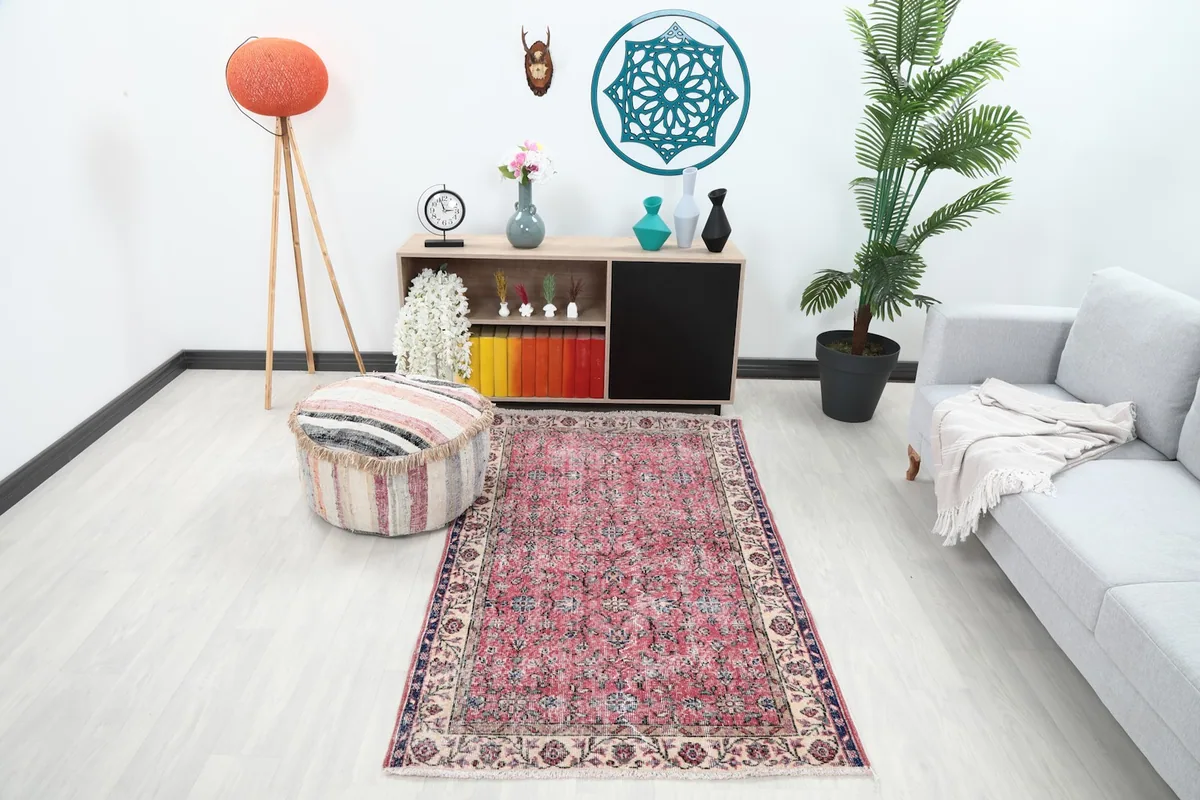 Rose and cream floral rug in a modern living room setting with a gray sofa and wooden furniture.