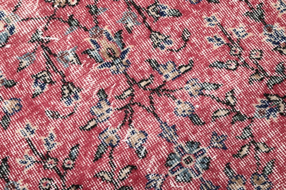 Close-up of the low wool pile, showing the hand-knotted texture and faded rose and blue colors.