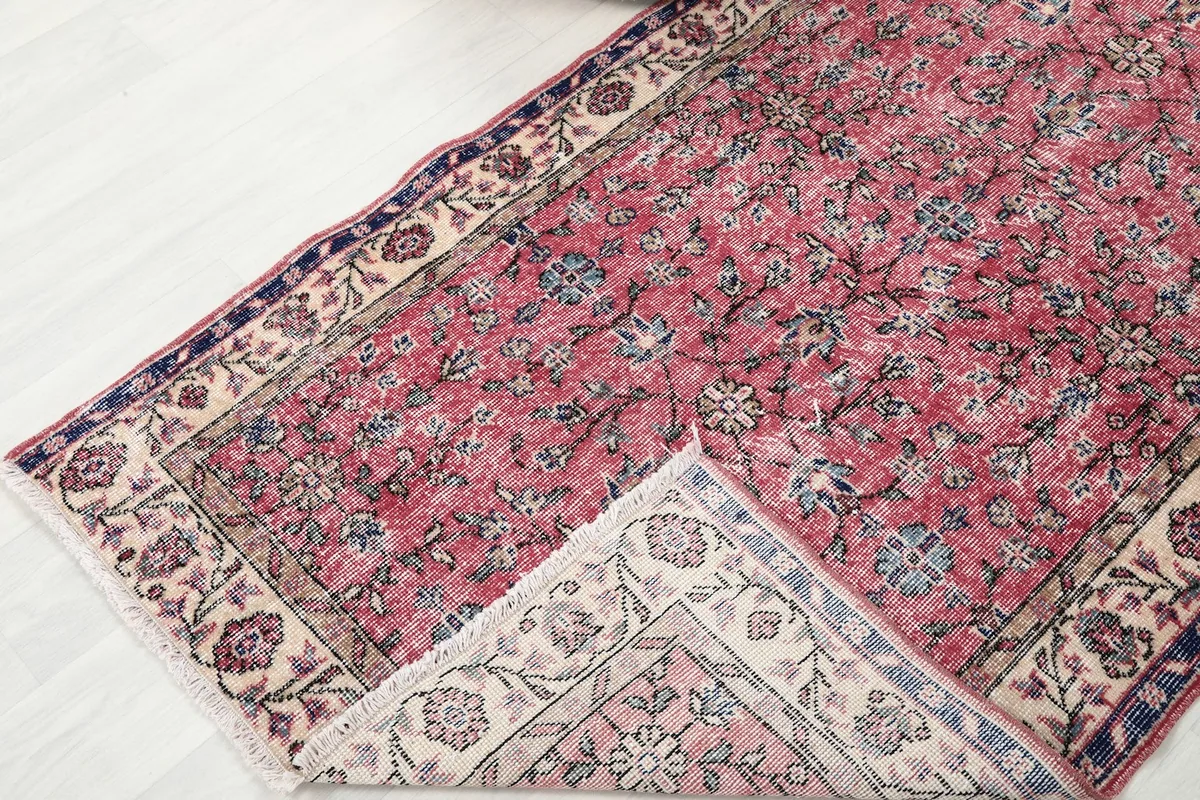 Corner of the rug folded back, revealing the reverse side of the hand-knotted wool on cotton foundation.