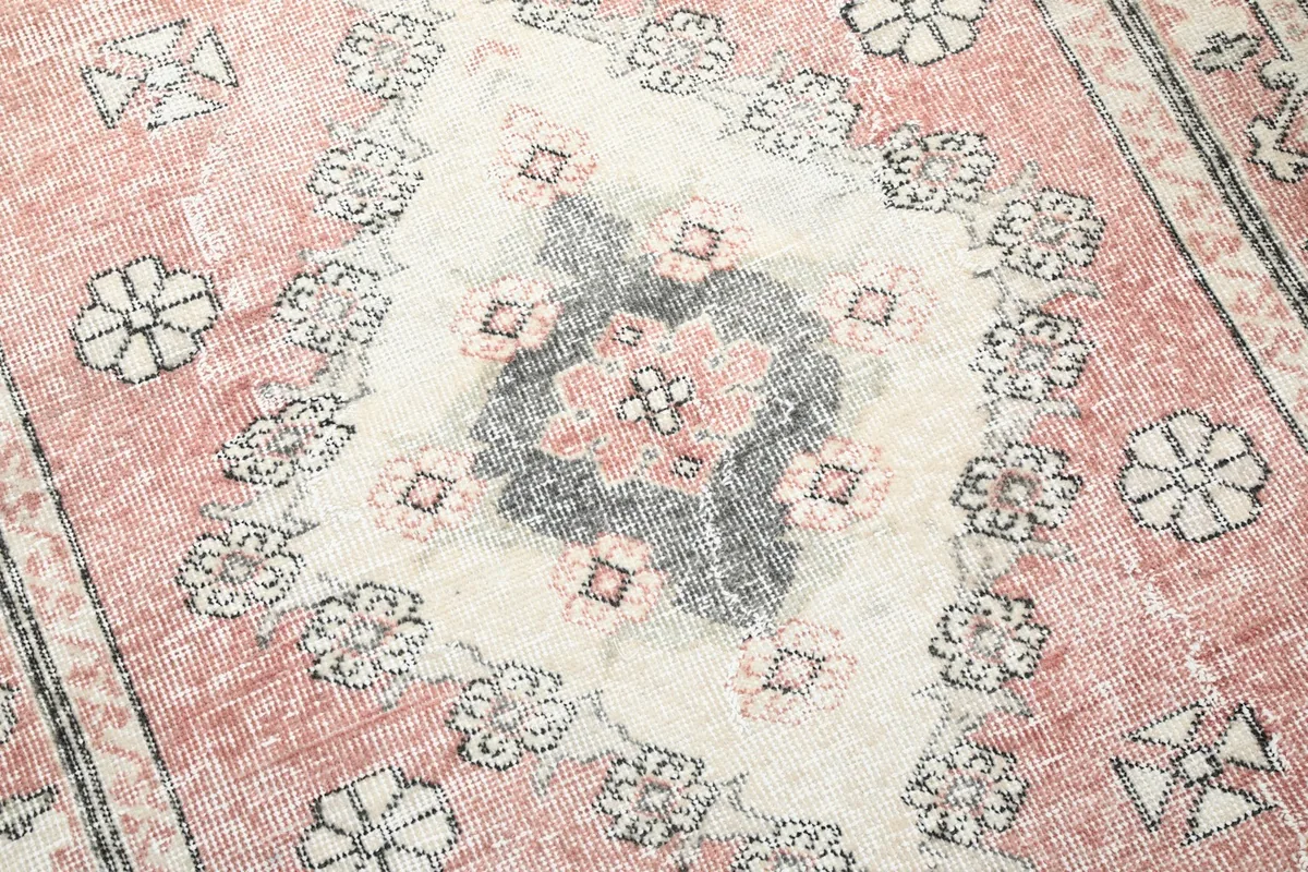 Close-up of the distressed rose and gray colors within the rug's central pattern