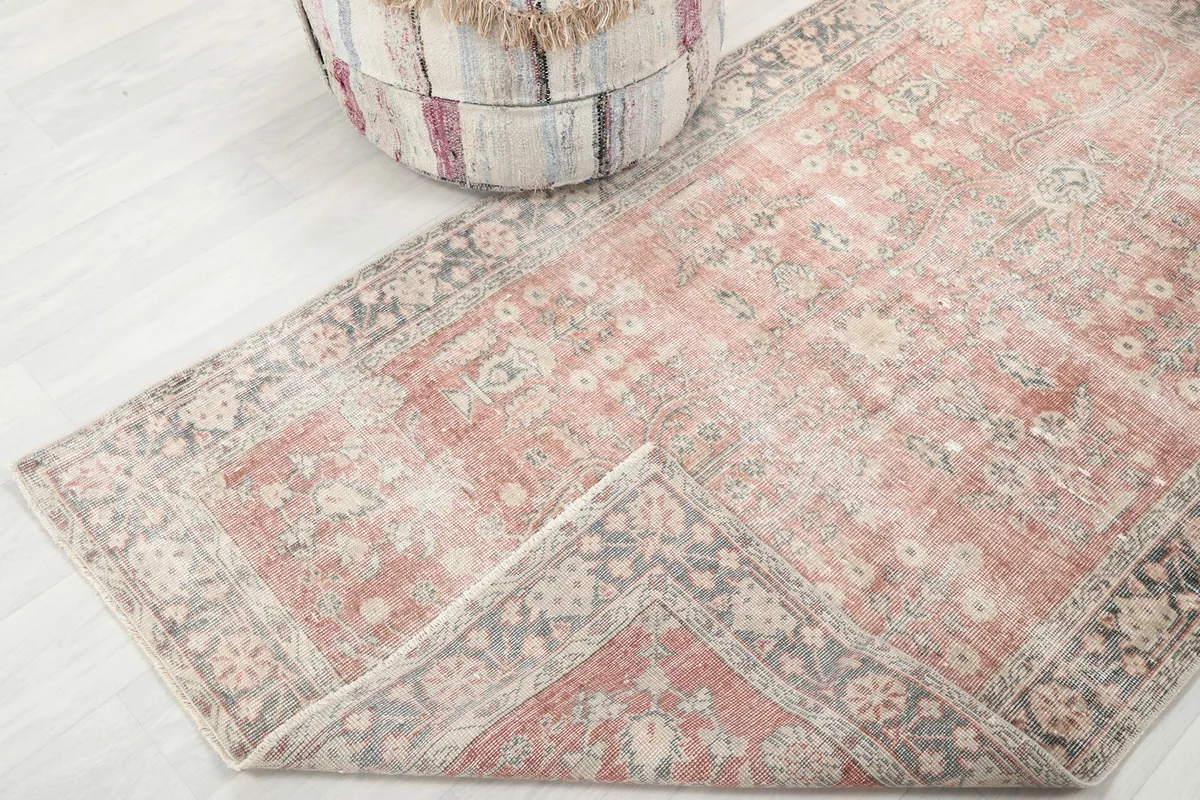 Corner of the rose rug folded back to reveal the density of the hand-knotted weave and foundation