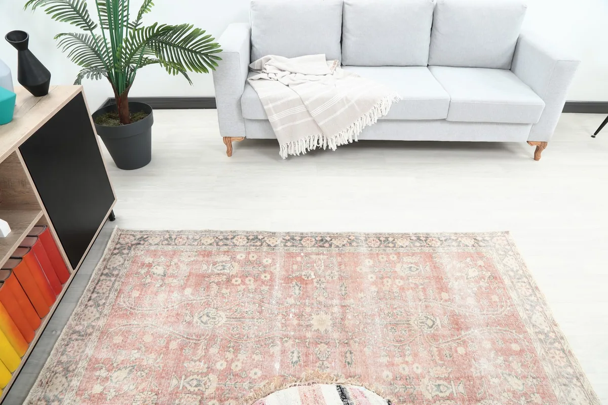 Overhead view of the vintage rug in a room setting, highlighting its muted rose and gray colors