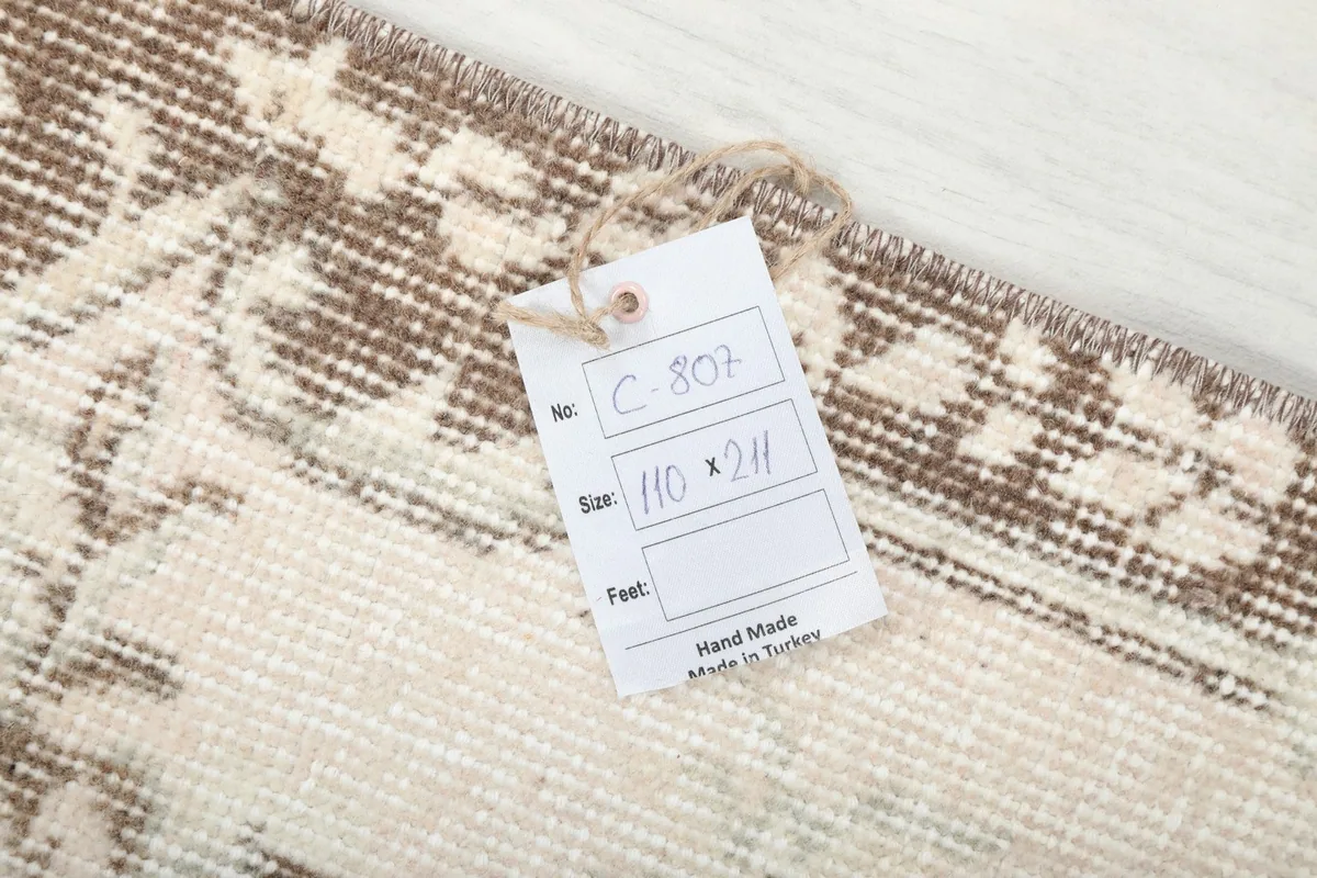 Tag showing the rug's dimensions in centimeters and origin, attached to the corner