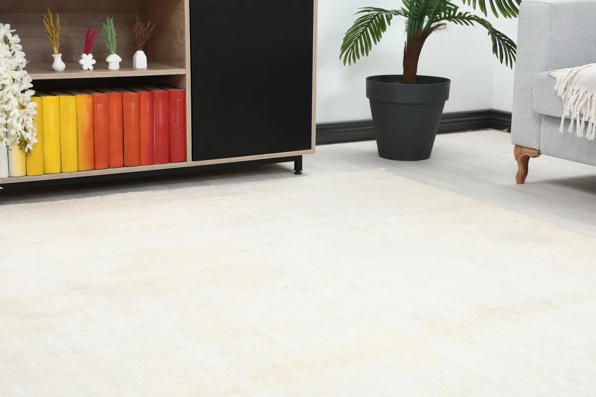 Close-up of the cream rug's subtle geometric pattern and low pile near a wooden cabinet.