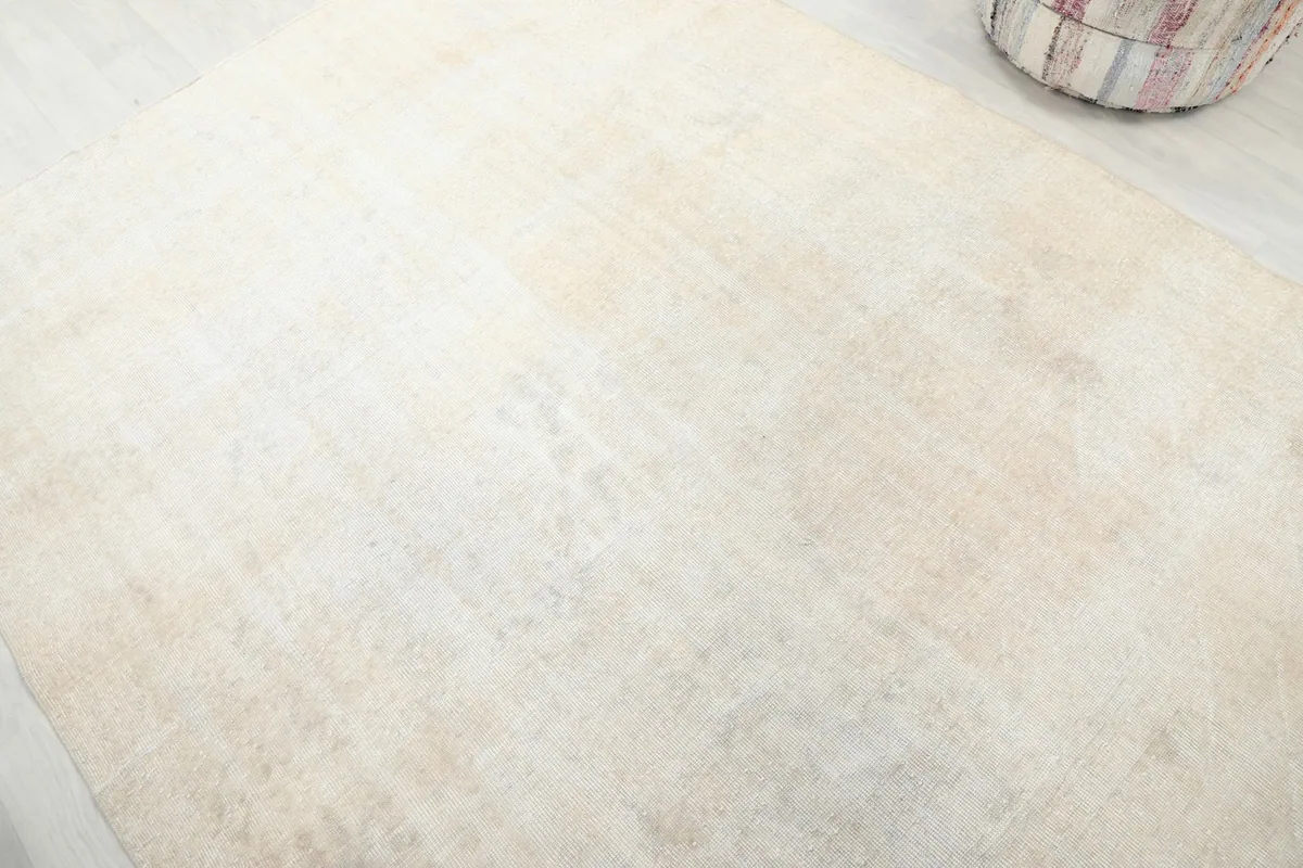 Detailed view of the rug's surface, highlighting the faded cream tones and texture.