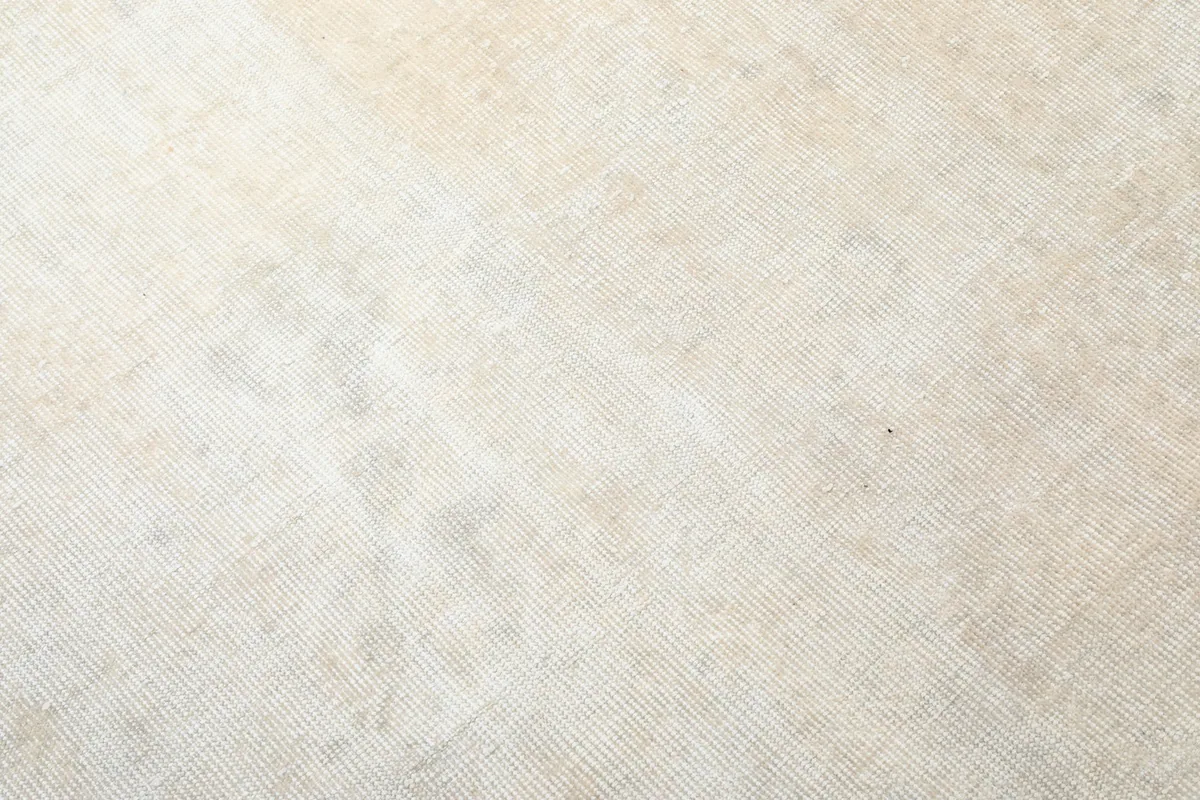 Extreme close-up showing the low pile and hand-knotted wool texture of the vintage rug.