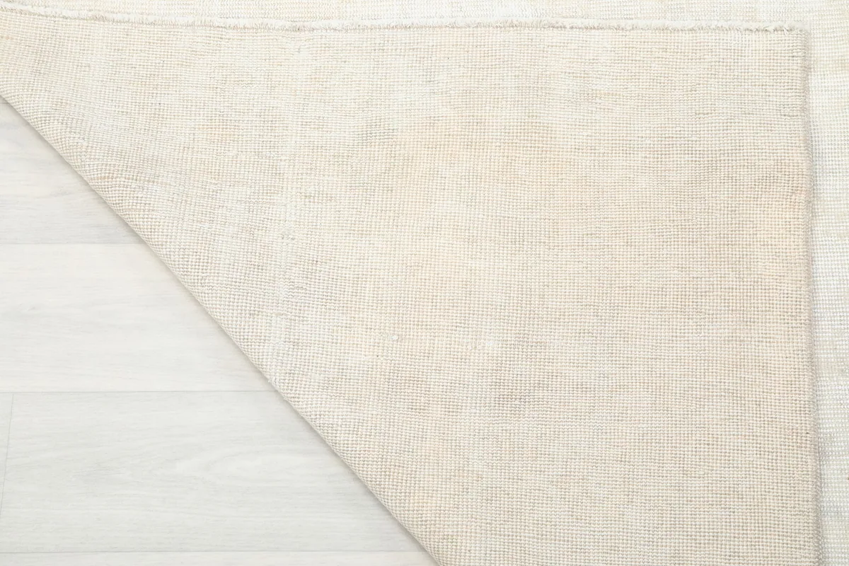 Corner of the rug folded back to show the cotton foundation and reverse side of the hand-knots.