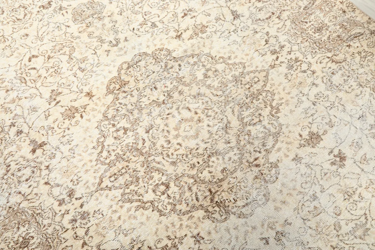 Close-up detail of the central medallion and surrounding floral motifs in ivory and tan.