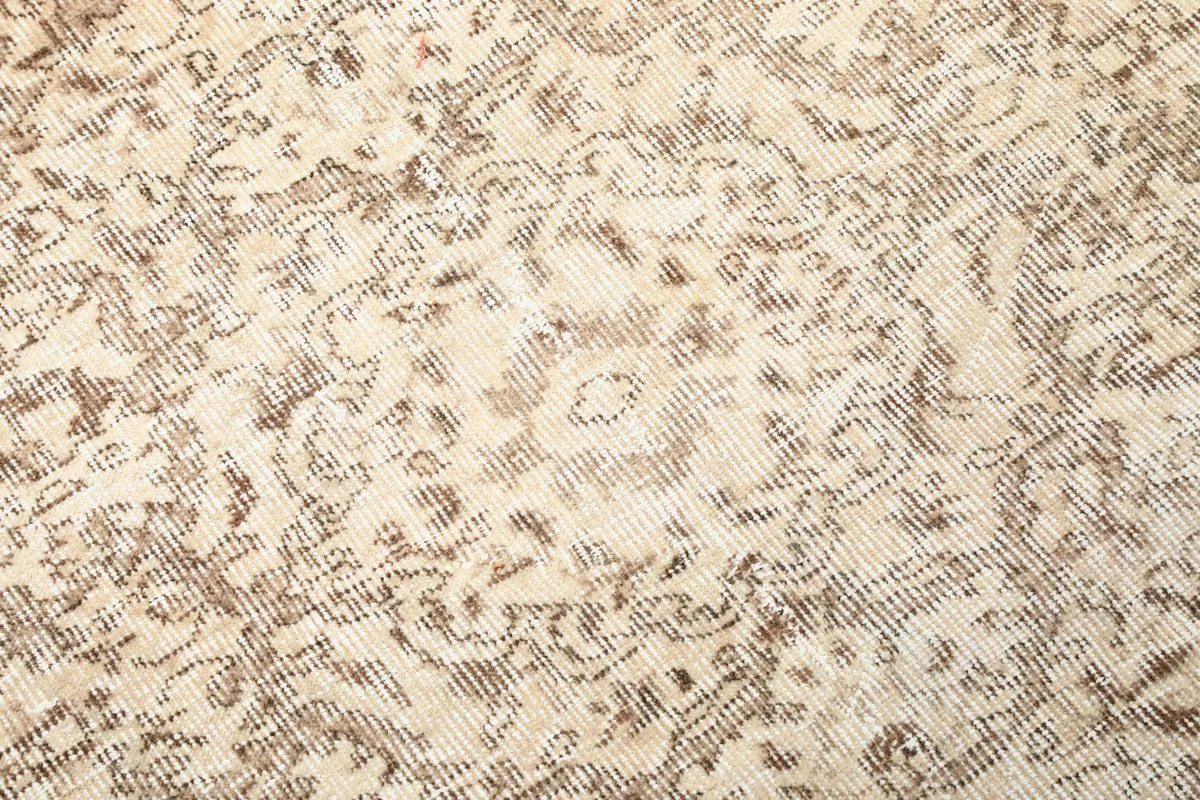 Textural detail of the hand-knotted wool pile, showing faded tan patterns.