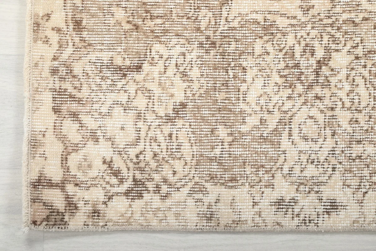 Close-up of the rug's edge, revealing the subtle border design and slight wear.