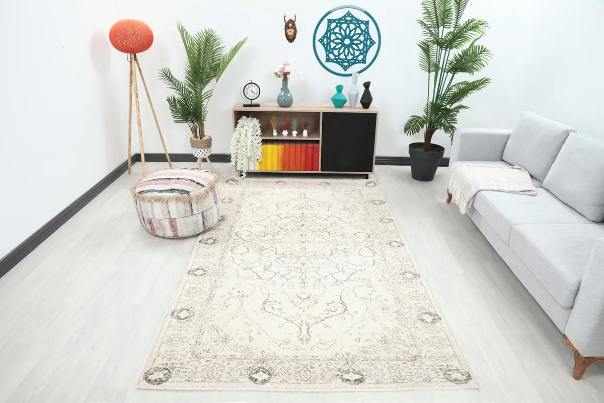 Vintage ivory rug in a modern living room setting with plants and a gray sofa