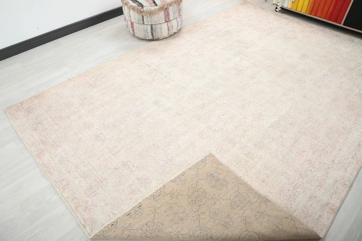 Corner of the rug folded back to reveal the cotton foundation and reverse side of the hand-knotting.