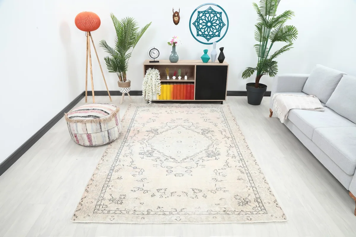 Vintage ivory rug displayed in a living room setting with a light gray sofa and modern decor.
