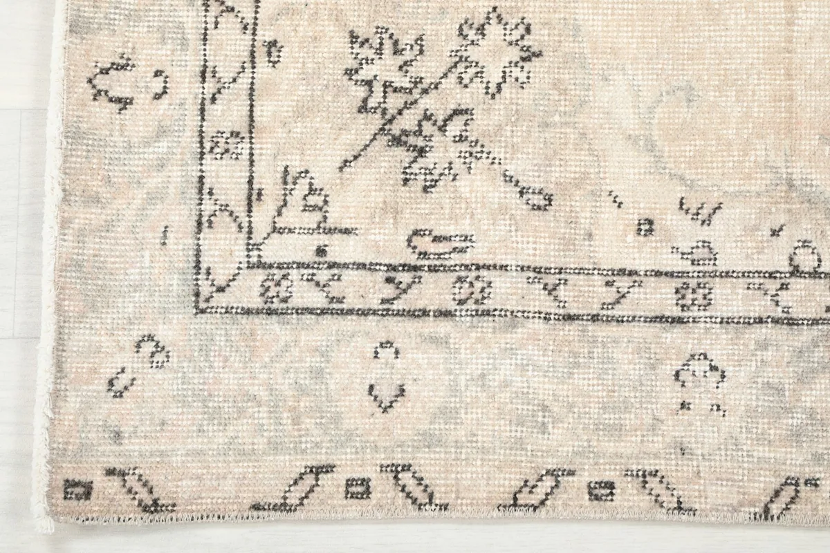 Corner detail of the rug, showing the intricate charcoal border patterns and fringe.