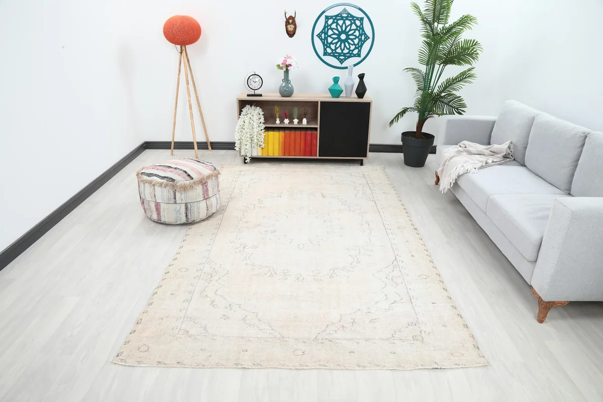 Vintage ivory rug displayed in a living room setting with a light gray sofa and modern decor.