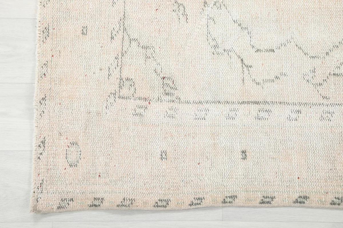 Close-up of the rug's border design, displaying geometric elements and the worn edge.