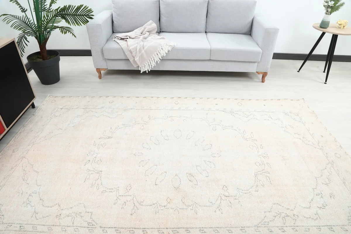 Overhead view of the ivory rug in a room, showing its central medallion and overall layout.