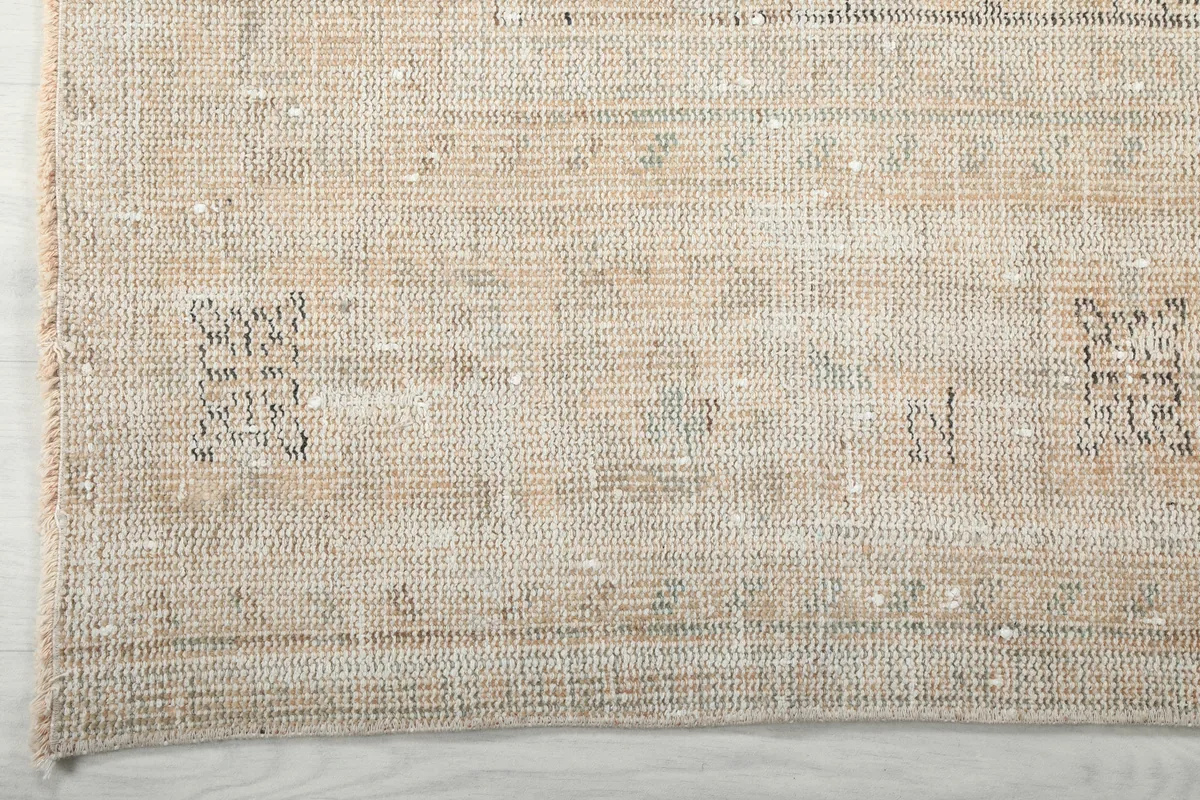 Close-up of the rug's edge, revealing the subtle variations in beige and ivory tones.
